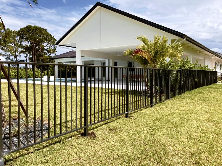 Modern white house with a sloped roof, featuring Rosewood Fencing black metal fence and well-kept green lawn
